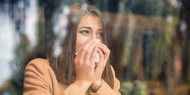 A woman blows her nose